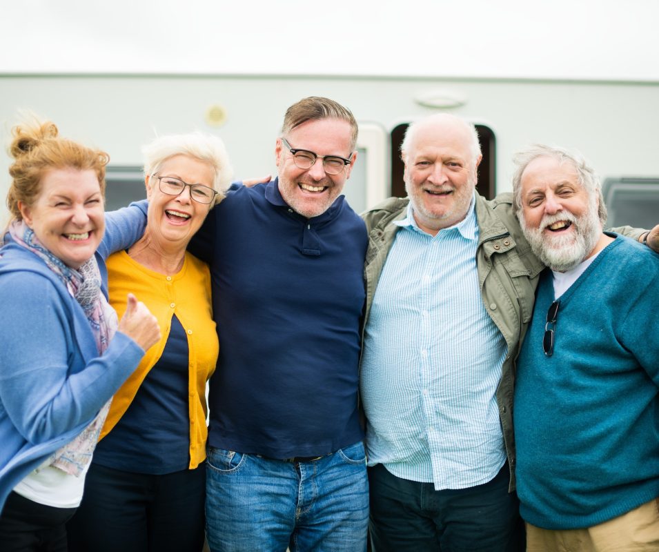 Group of five smiling older adults standing together outdoors, showing friendship and joy. Old people asually dressed and appear happy and relaxed. Happy senior people.