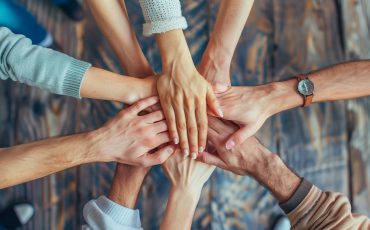 A group of people are holding hands in a circle. The people are of different ages and genders. Concept of unity and togetherness